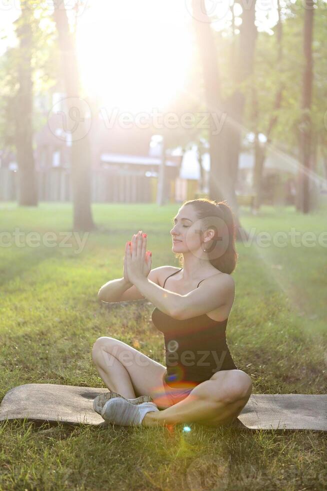 Young woman meditating outdoors in summer park photo
