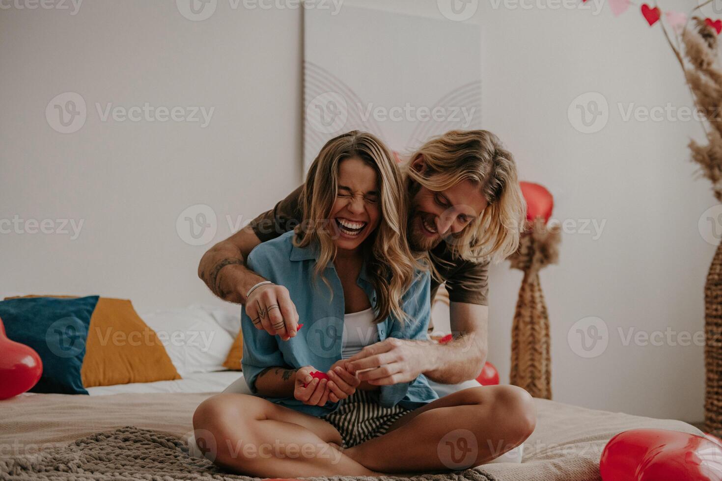 Playful young loving couple having fun together while celebrating Valentines day at home photo