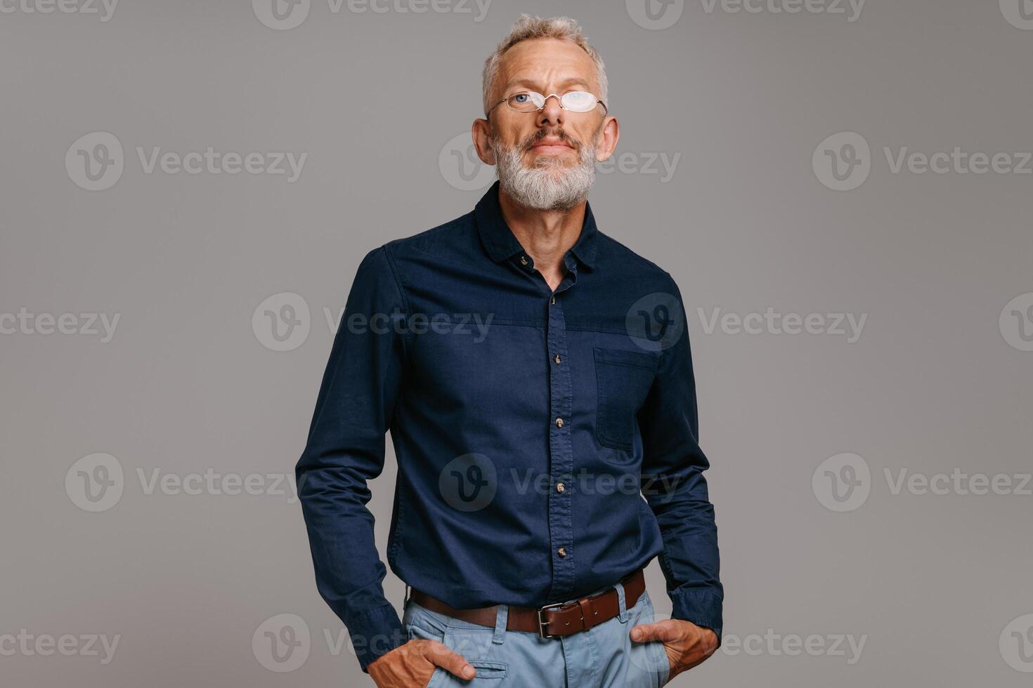 Confident mature man in smart casual wear looking at camera on gray background photo