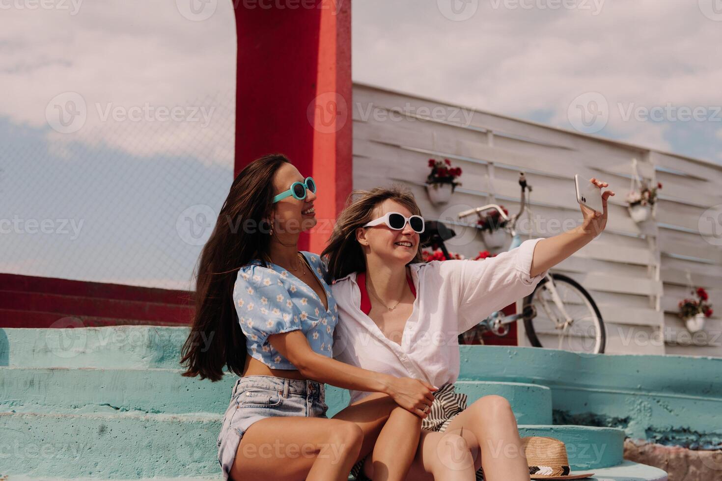 Two attractive young women making selfie and smiling while sitting outdoors together photo