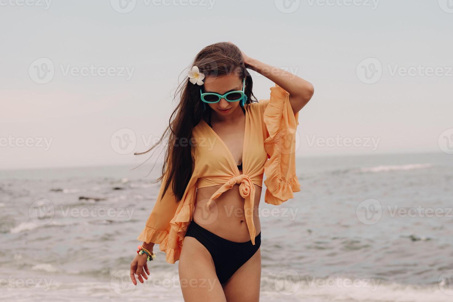 Beautiful young woman in boho styled crop top enjoying summer day on the beach photo