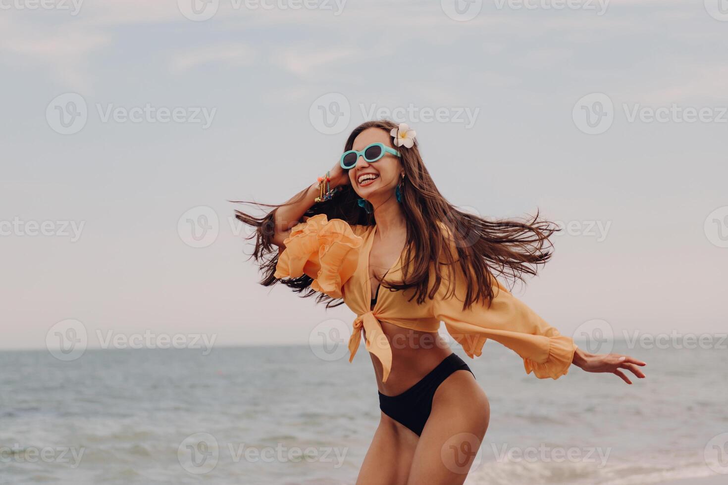 Attractive young woman in swimwear running and looking happy while enjoying day seaside photo