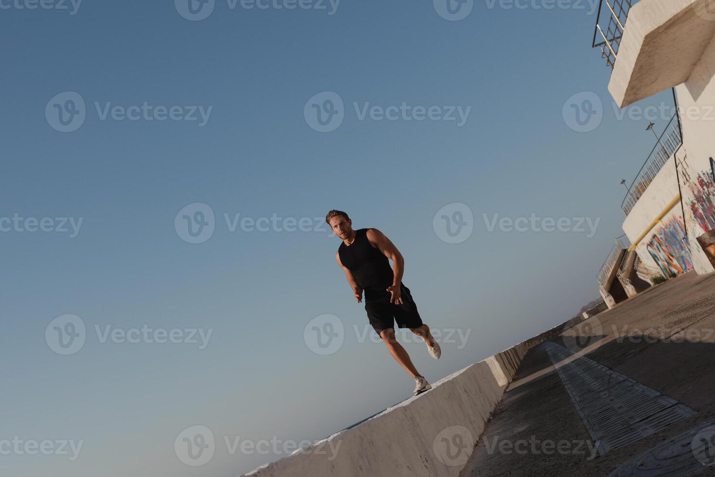 Confident young man in sports clothing enjoying his everyday morning jog outdoors photo