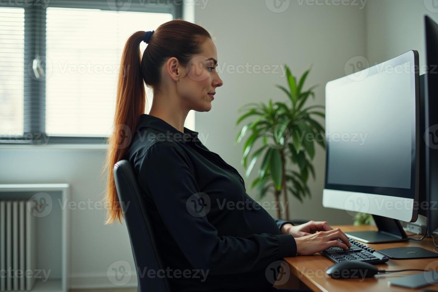 photo of pregnant woman working sitting at her desk in her office,