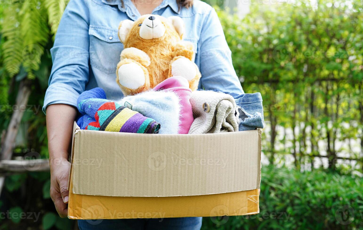 Volunteer collect cloth and doll in cardboard box to donate. photo