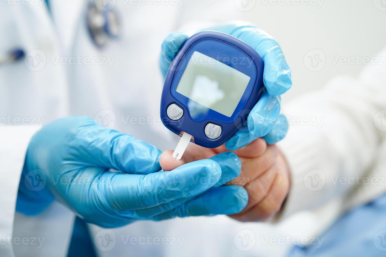 Asian doctor using digital glucose meter for check sample blood sugar level to treatment diabetes. photo