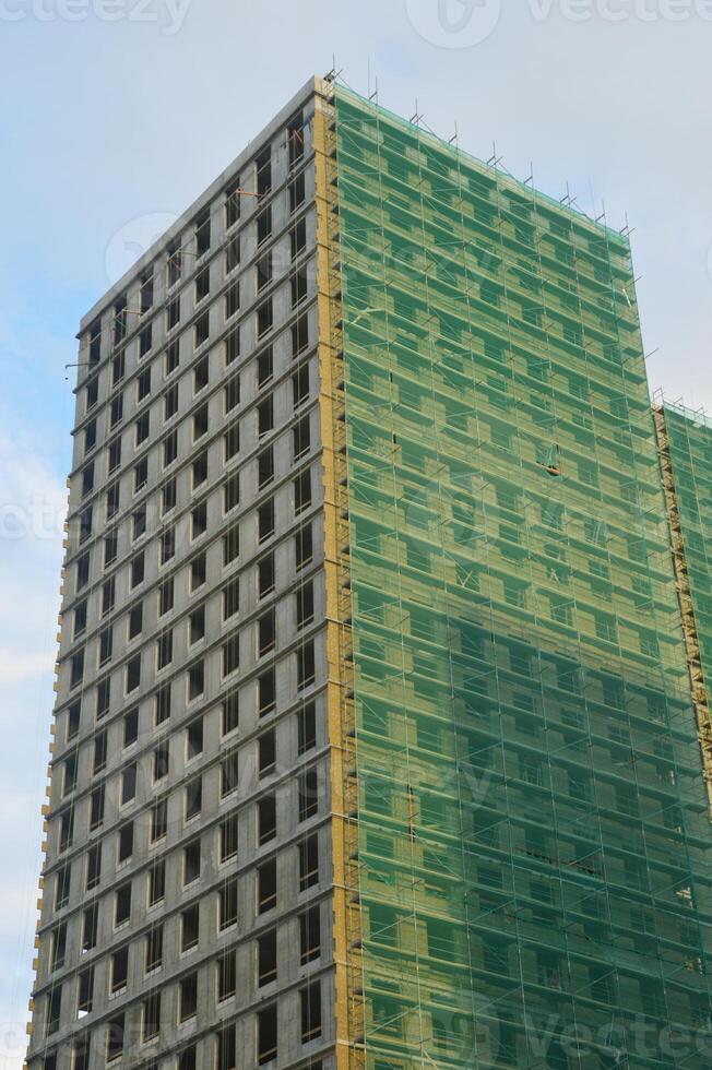 A multi-storey residential building under construction against the blue sky. A fragment of the facade of modern urban architecture. photo