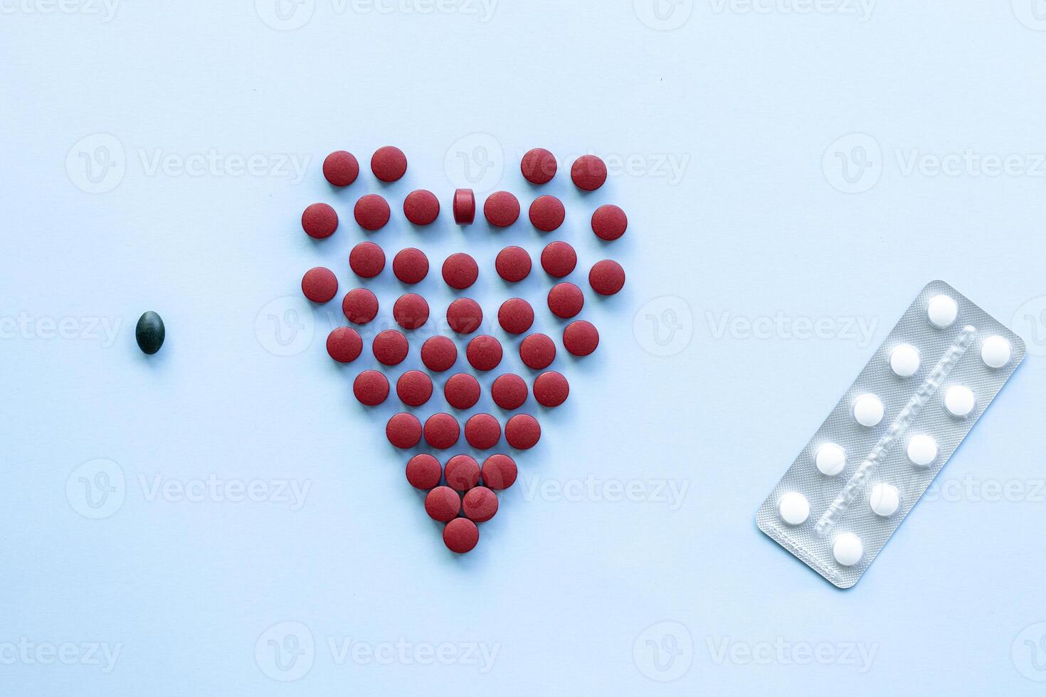 abstract on the topic of a healthy heart, heart disease and the like. bright red pills in the shape of a heart on a bright blue plain background photo