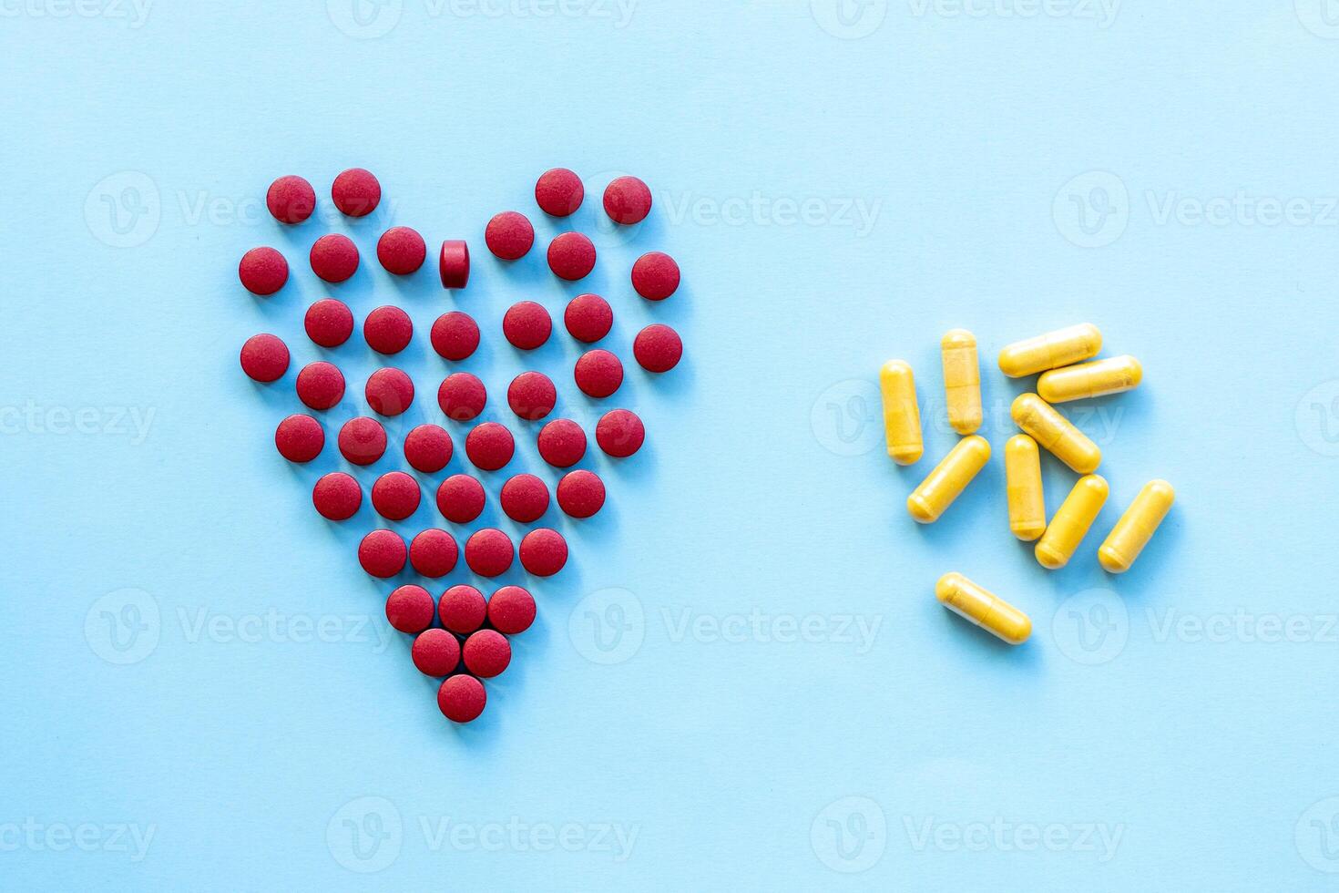 abstract on the topic of a healthy heart, heart disease and the like. bright red pills in the shape of a heart on a bright blue plain background photo