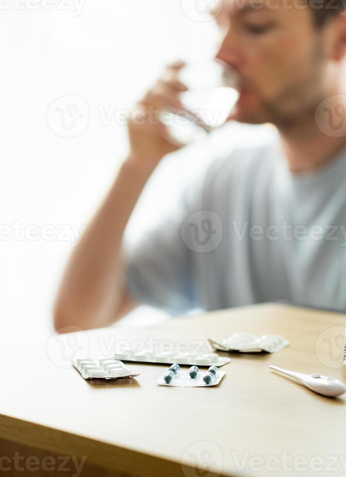 man takes medicine, patient drinks pills, blisters with pills on the table, medicine concept photo