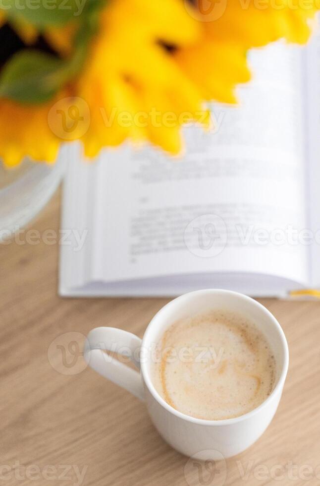 summer morning atmosphere, open book next to bouquet of flowers and cup of coffee, top view photo