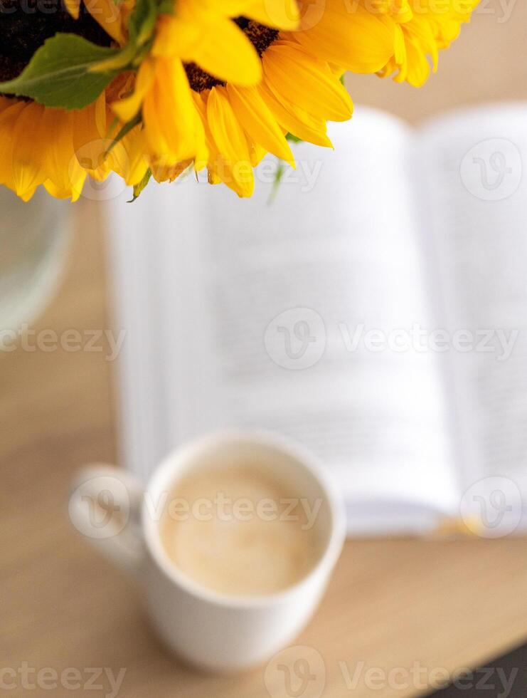 summer morning atmosphere, open book next to bouquet of flowers and cup of coffee, top view photo