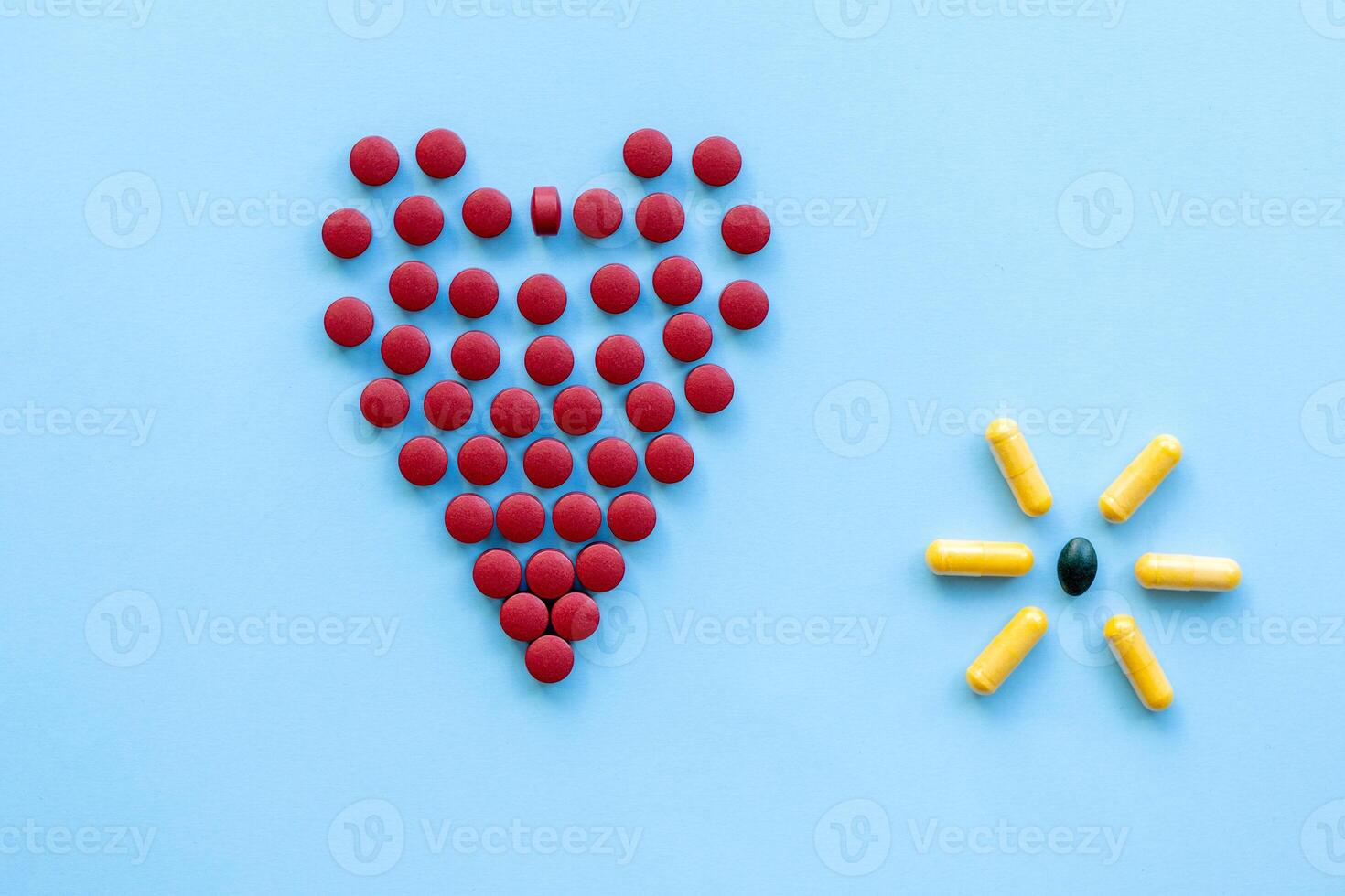 abstract on the topic of a healthy heart, heart disease and the like. bright red pills in the shape of a heart on a bright blue plain background photo