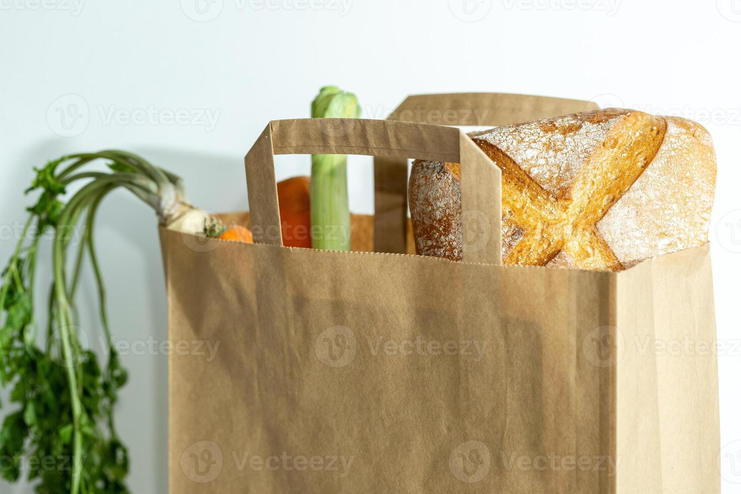 Kraft paper bag filled with fresh vegetables and bread, on white background, fresh vegetable delivery and shopping at local markets, farm produce photo