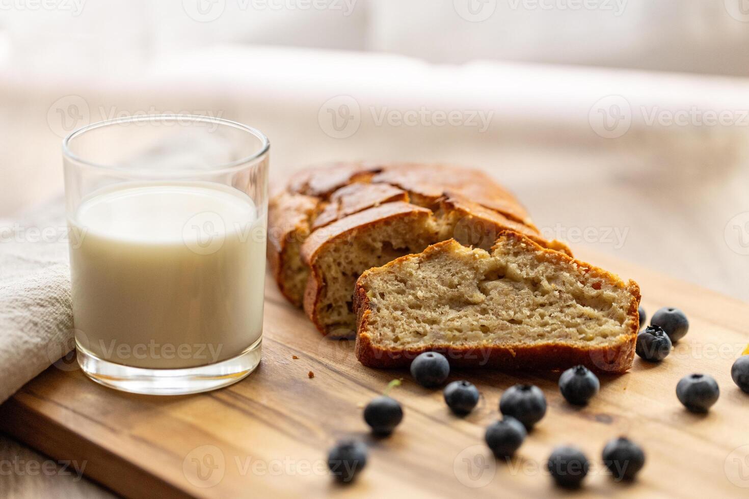 glass of milk and sweet homemade banana bread with crispy crust on a wooden board, dessert photo