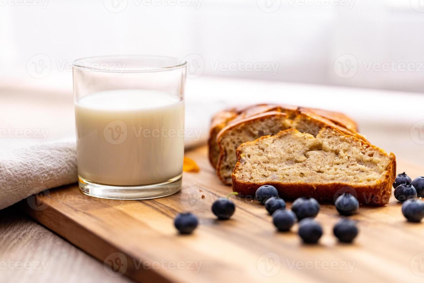 glass of milk and sweet homemade banana bread with crispy crust on a wooden board, dessert photo