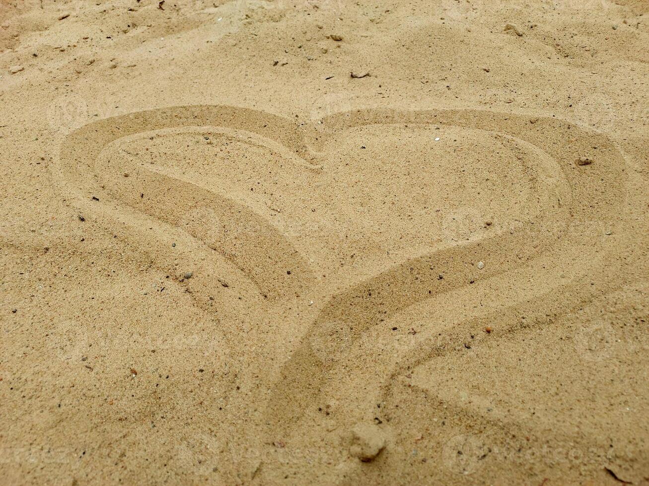 Heart drawn in beach sand. Summer vacation and love concept. Design for greeting cards, invitations, and postcards. Top view, soft daylight photo