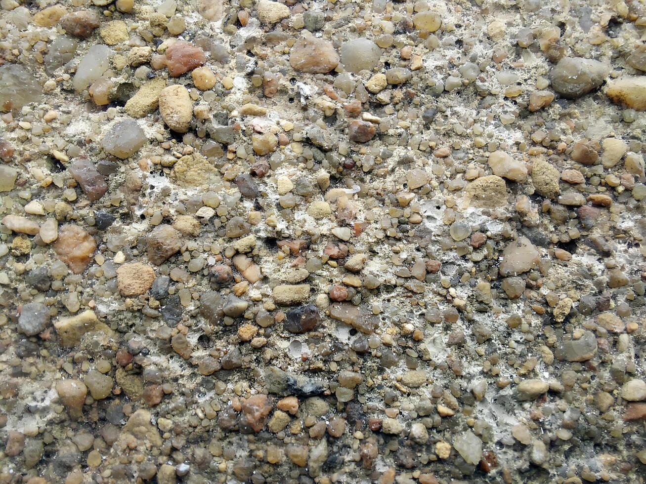 Texture of small sea pebbles. Natural stone seamless background. Rough surface of pebble stone. Design for wallpaper, print, and interior. Top view, soft daylight photo