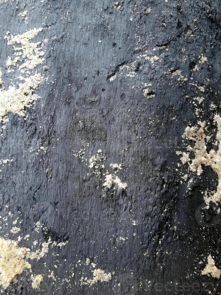 Burnt wood seamless texture partially covered with sand. Nature background. Design for wallpaper, print, and interior. Close-up, soft daylight. photo