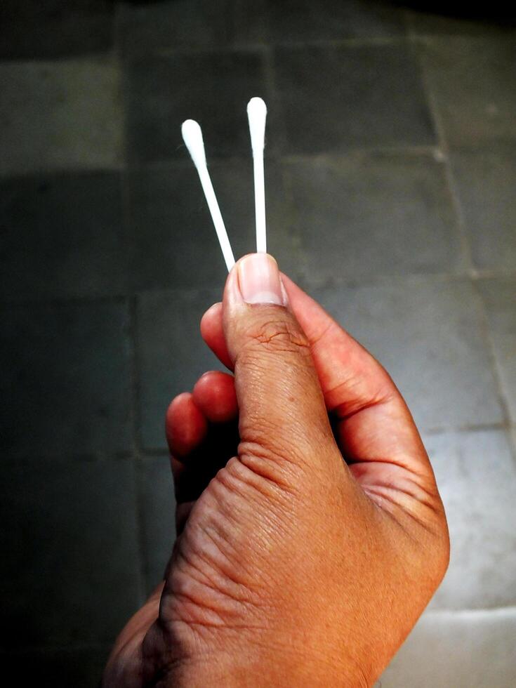 A hand holding two white cotton swabs. Concept of cleanliness and hygiene photo