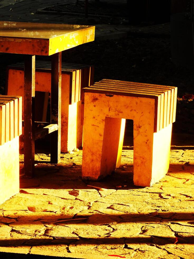 A yellow stool sitting and a table on the park with sunlight coming from the backside, creating calm and relax ambience photo