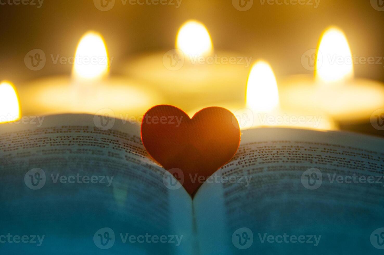 Heart space on top of a Bible with blurred candles background. Christianity and Religious concept photo