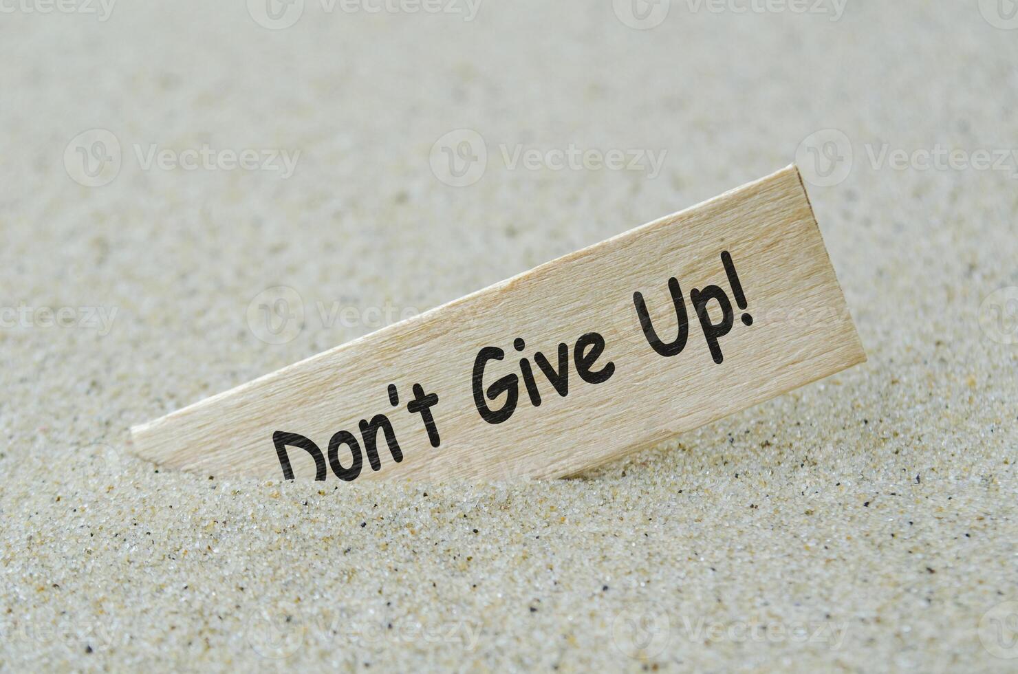 Do not give up text on wooden stick with beach sand background. Motivational concept photo