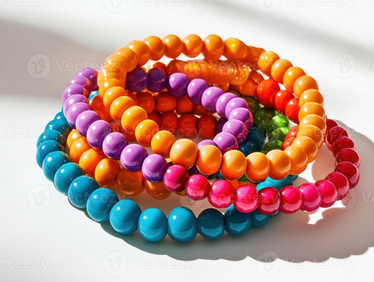 a stack of colorful bracelets on a white surface photo