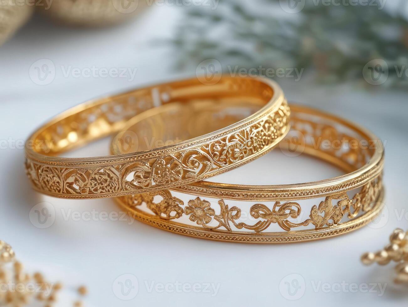 two gold bangles with intricate designs photo
