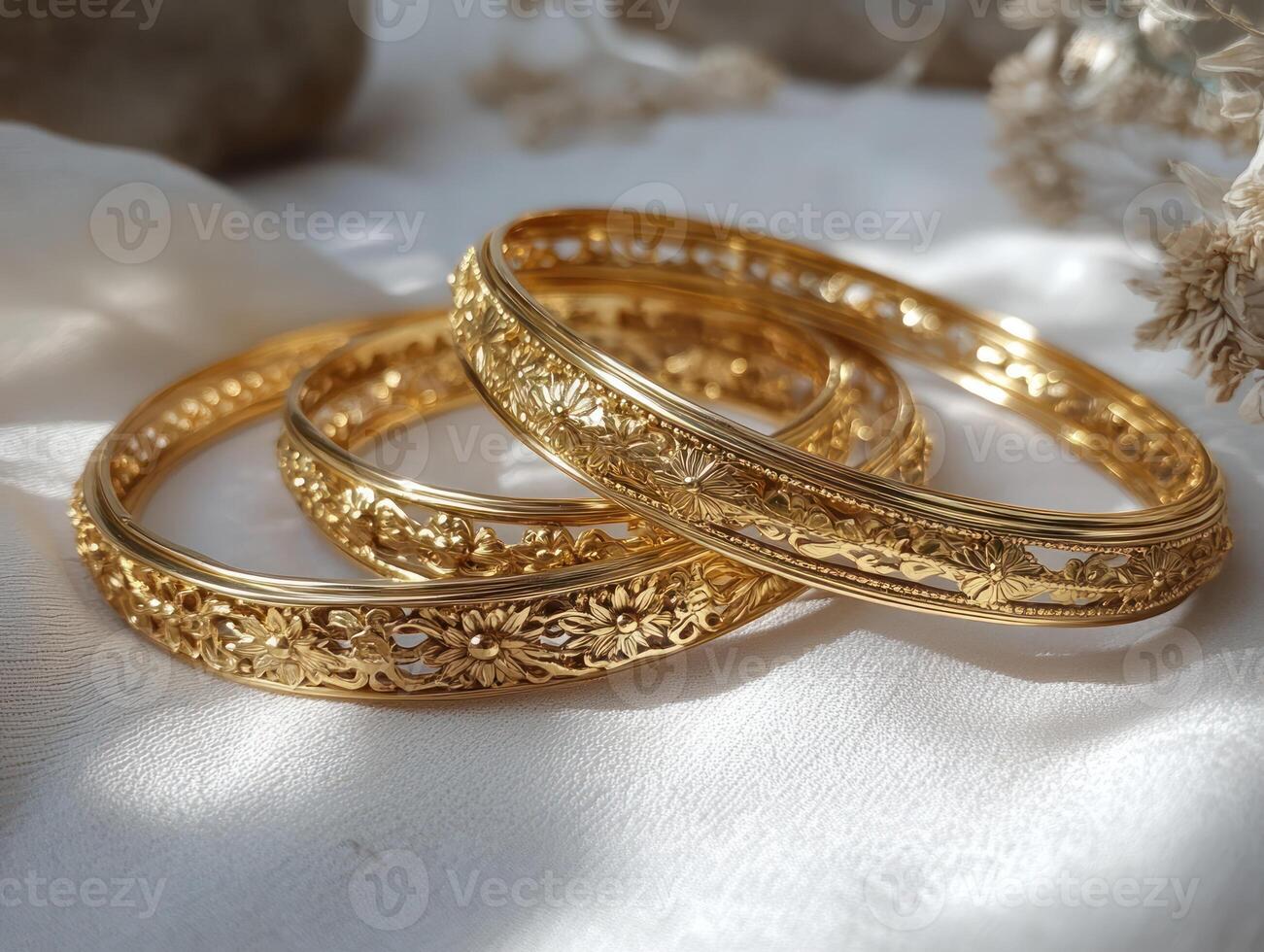 three gold bangles on a white cloth photo