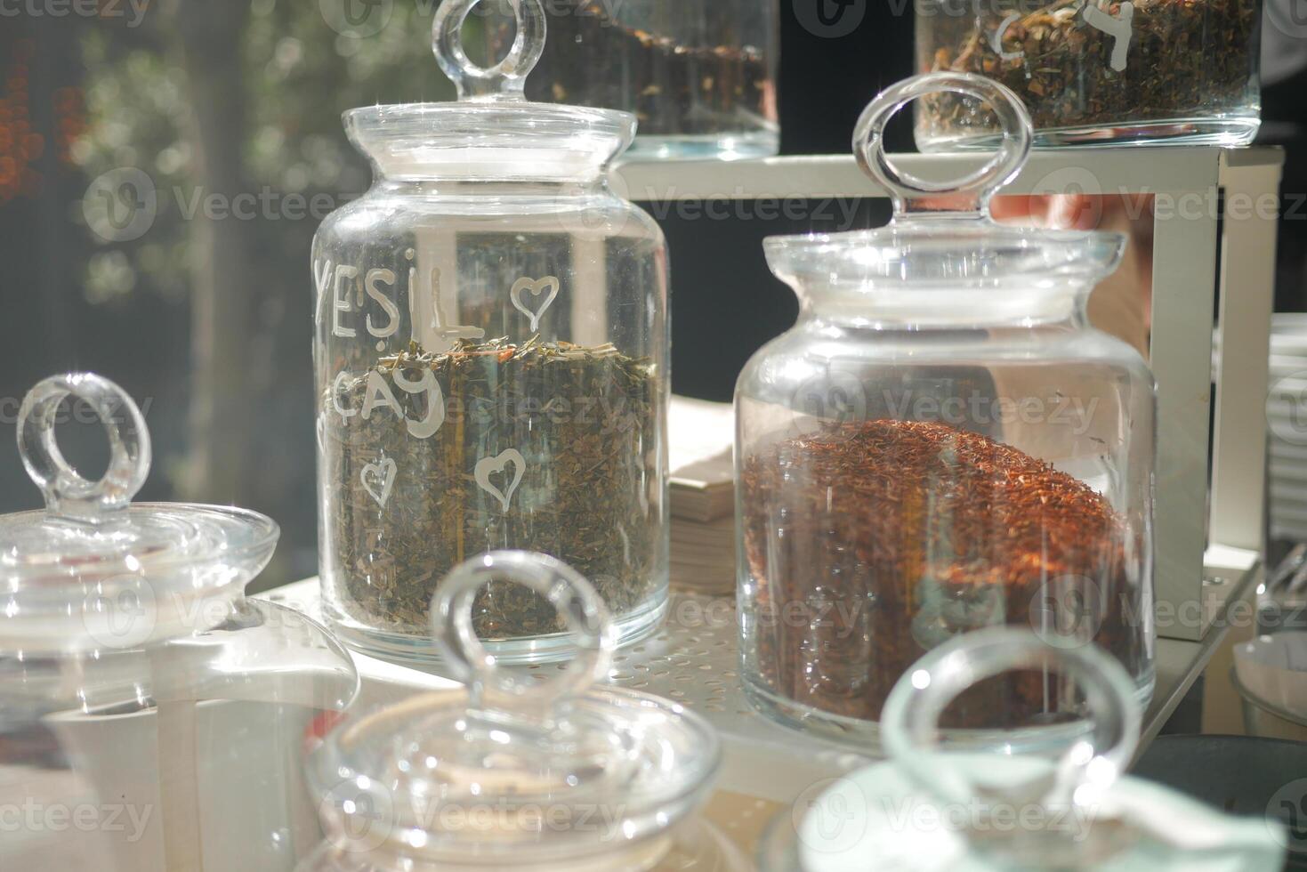 A detailed view of various jars filled with herbs and spices in a warm kitchen or cafe atmosphere photo