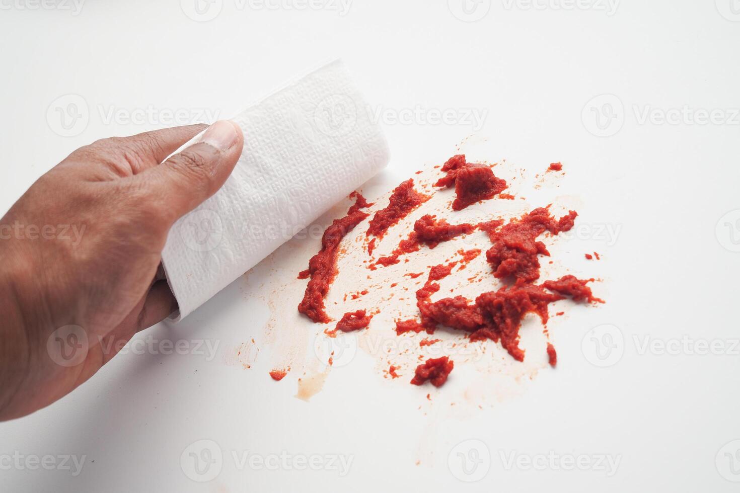 Carefully cleaning and removing a red liquid spill from a pristine white surface area photo