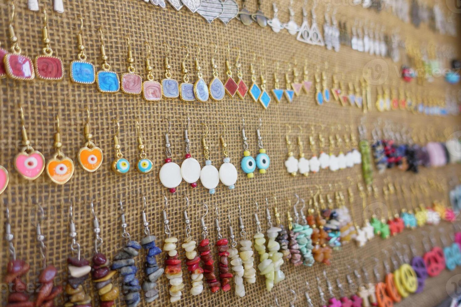 A Beautiful Collection of Colorful Handmade Earrings Gracefully Displayed on a Burlap Wall photo