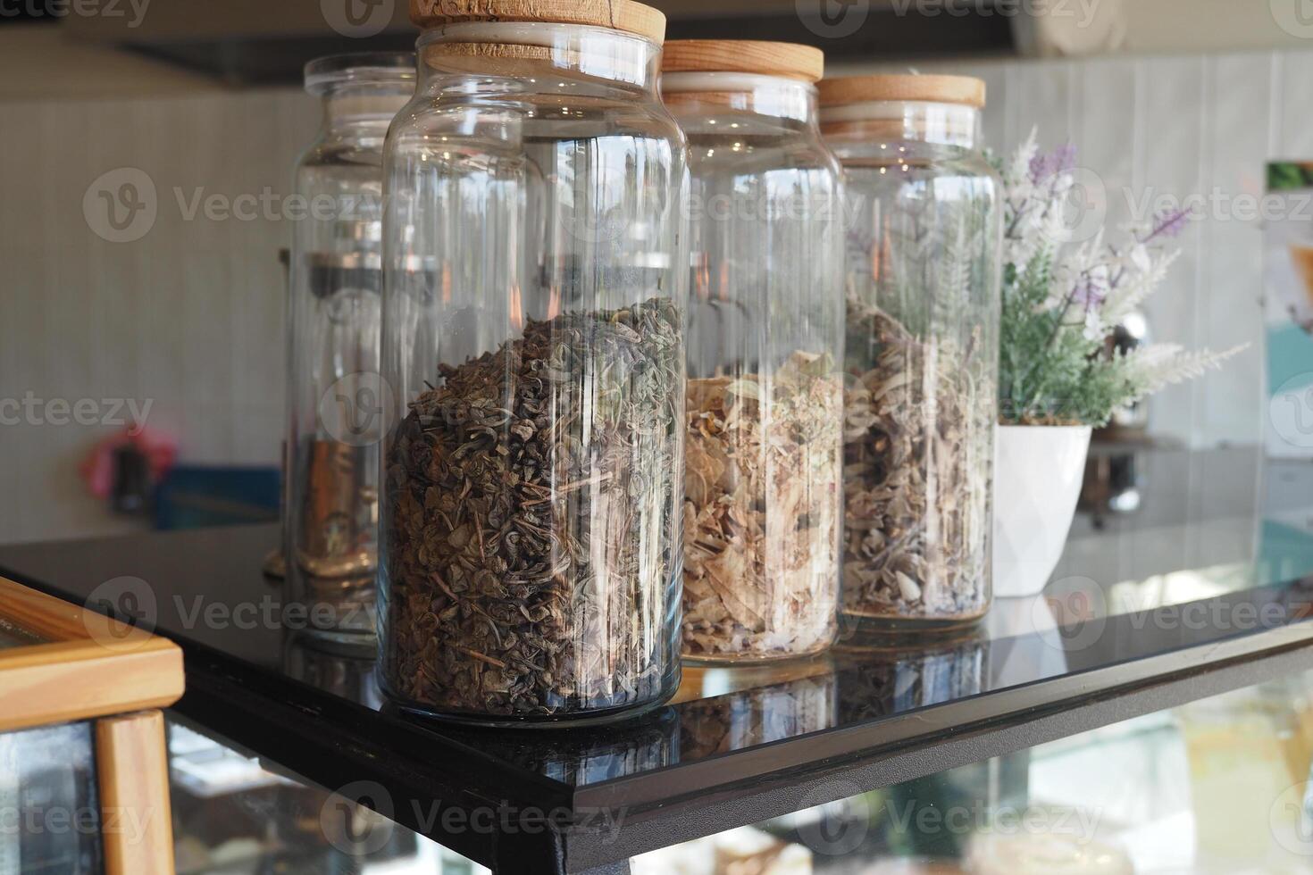 A detailed view of various jars filled with herbs and spices in a warm kitchen or cafe atmosphere photo