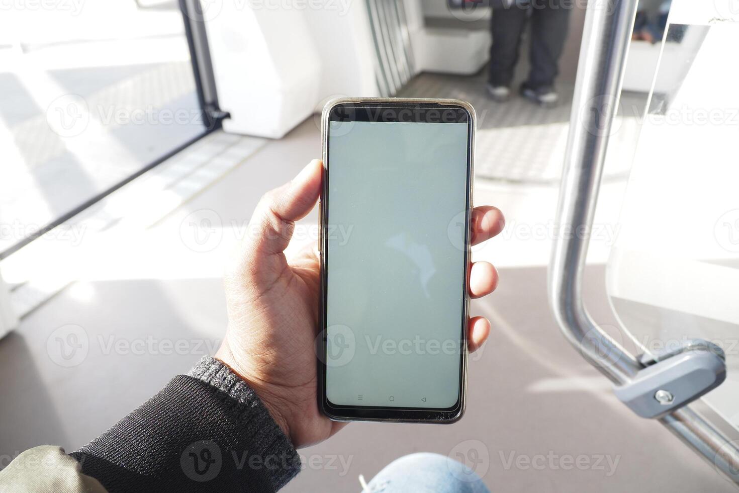 young man hand using smart phone with empty screen inside of metro train photo