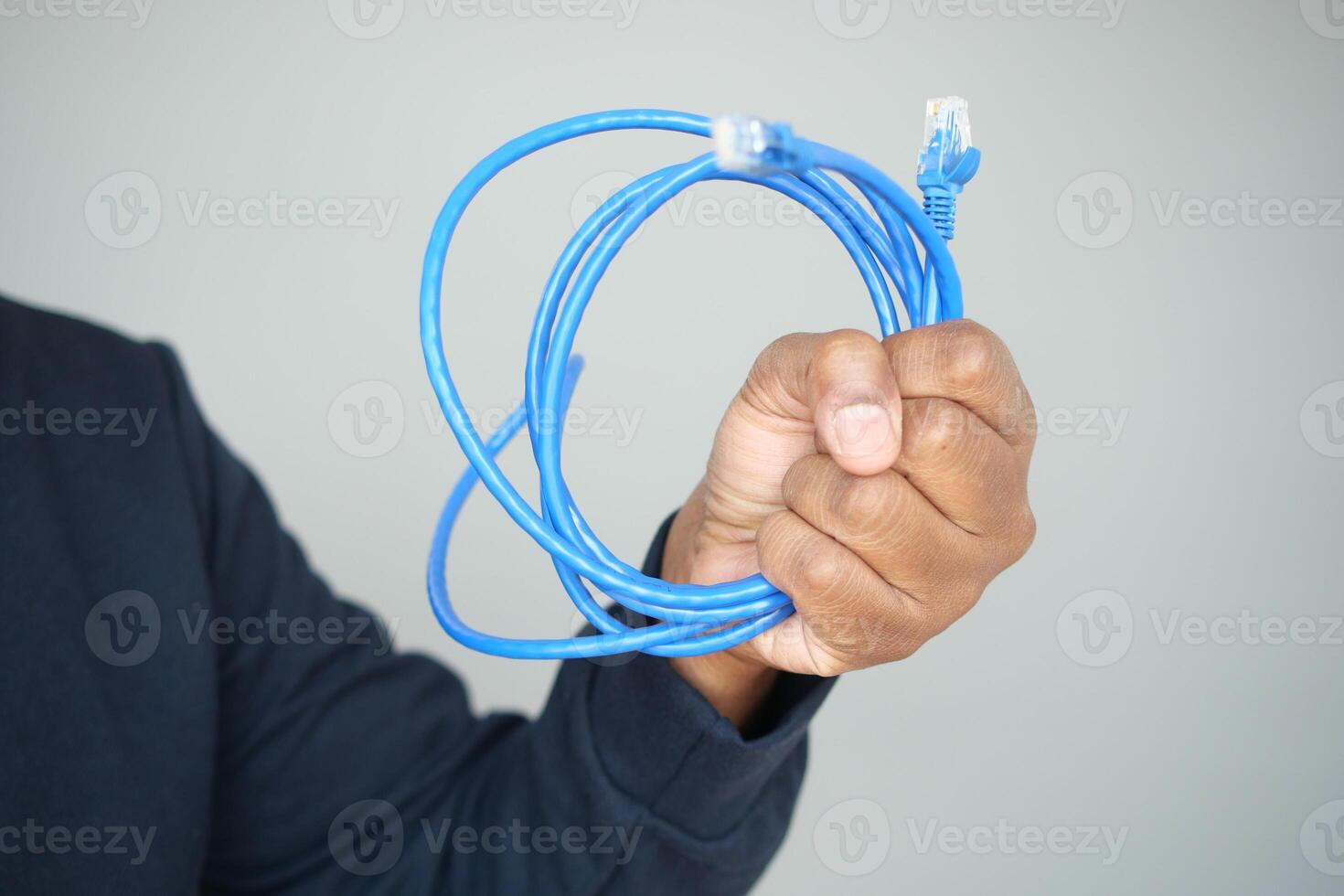 A closeup of hands holding a coiled blue Ethernet cable for a network connection photo