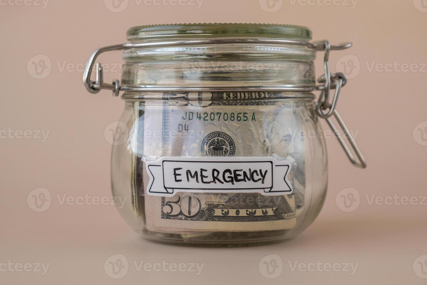 Glass jar full of American currency dollars cash banknote with text EMERGENCY. Preparation saving money. Moderate consumption and economy. Collecting money photo