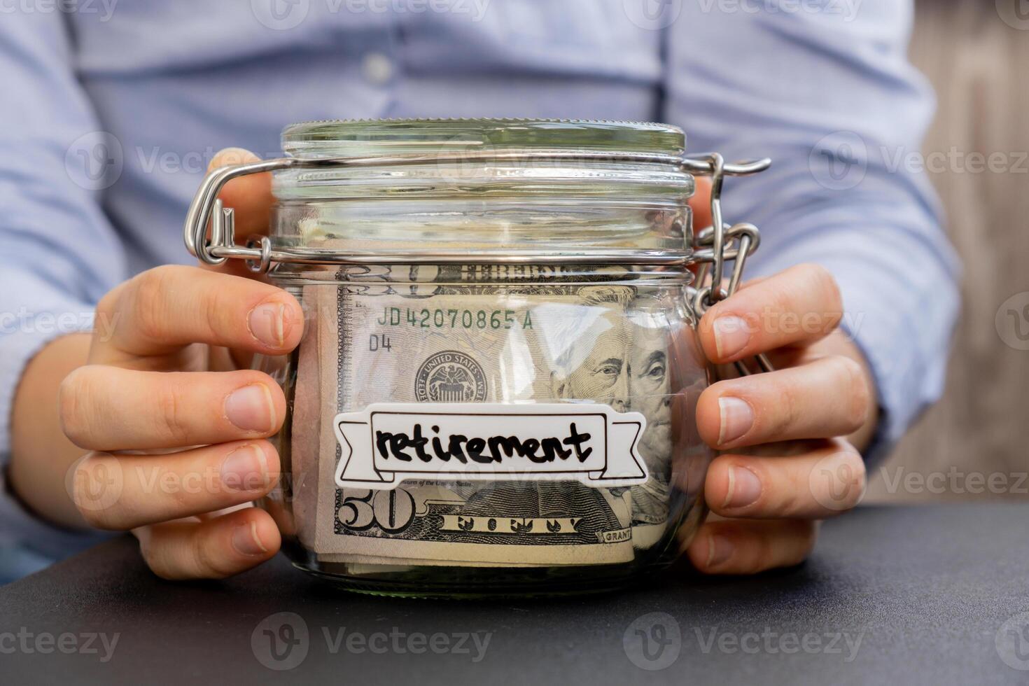 Unrecognizable woman holding Saving Money In Glass Jar filled with Dollars banknotes. RETIREMENT transcription in front of jar. Managing personal finances extra income for future insecurity background photo