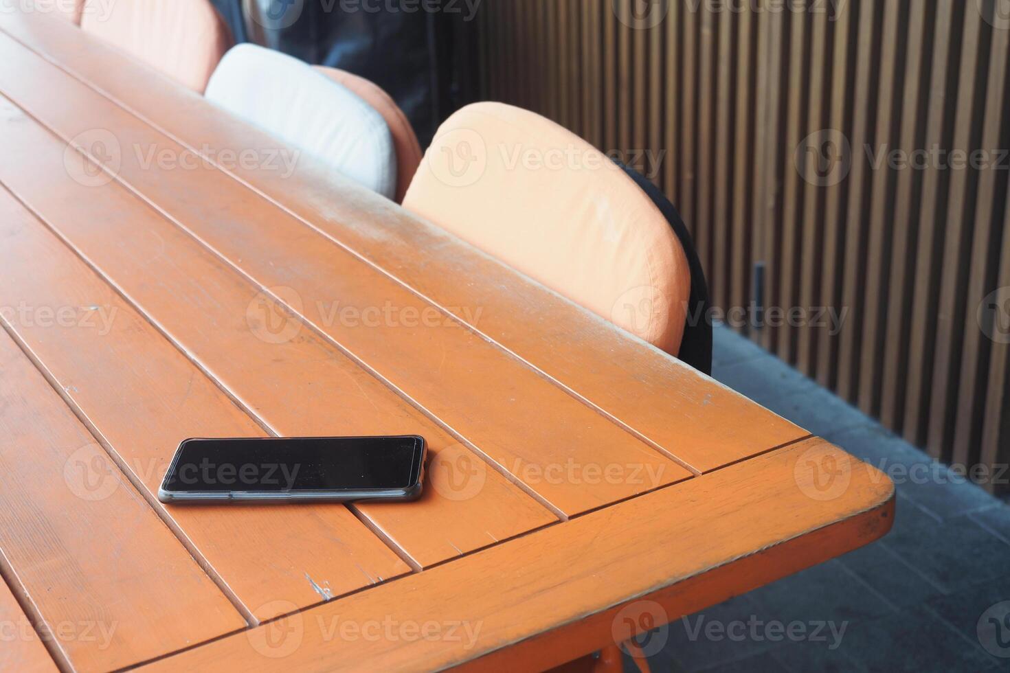 A Modern Workspace Featuring a Smartphone Resting on a Wooden Table Surface in an Office Setting photo