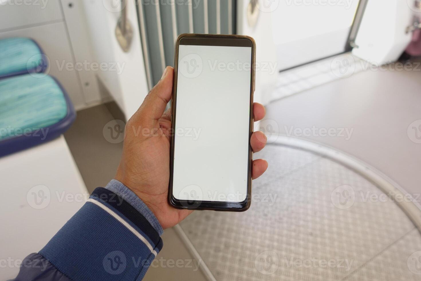 young man hand using smart phone with empty screen inside of metro train photo