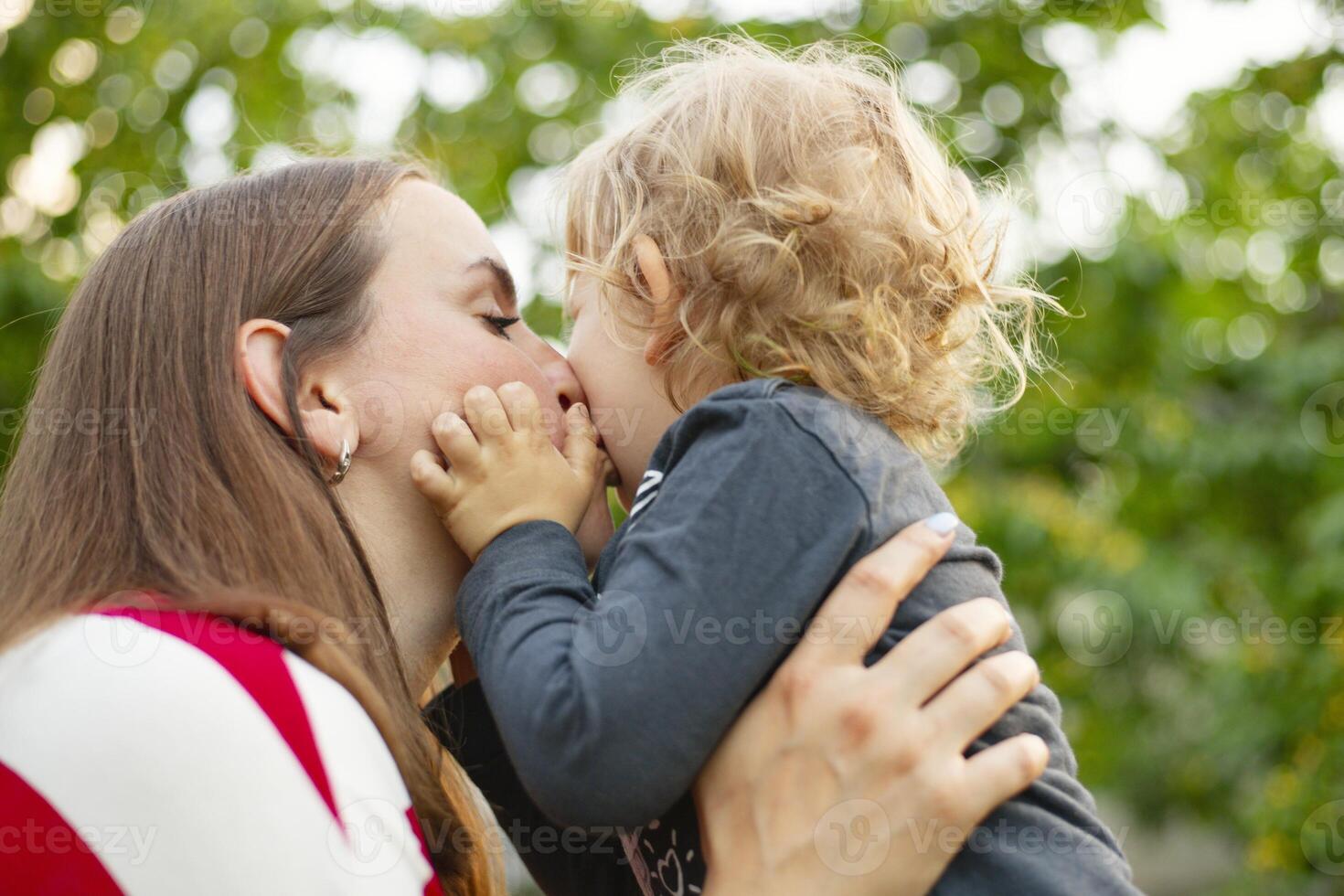 Happy mother and son hugging in love playing in the park. photo