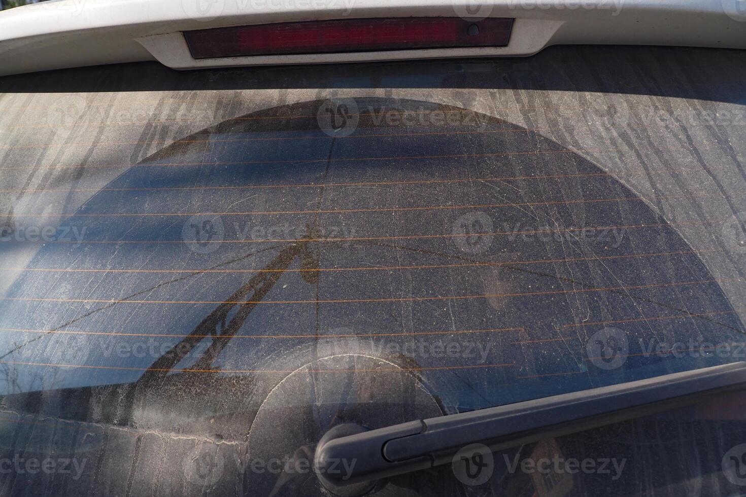 A Dusty Automobiles Rear Window Displaying a Unique Circular Pattern of Dirt and Grime photo