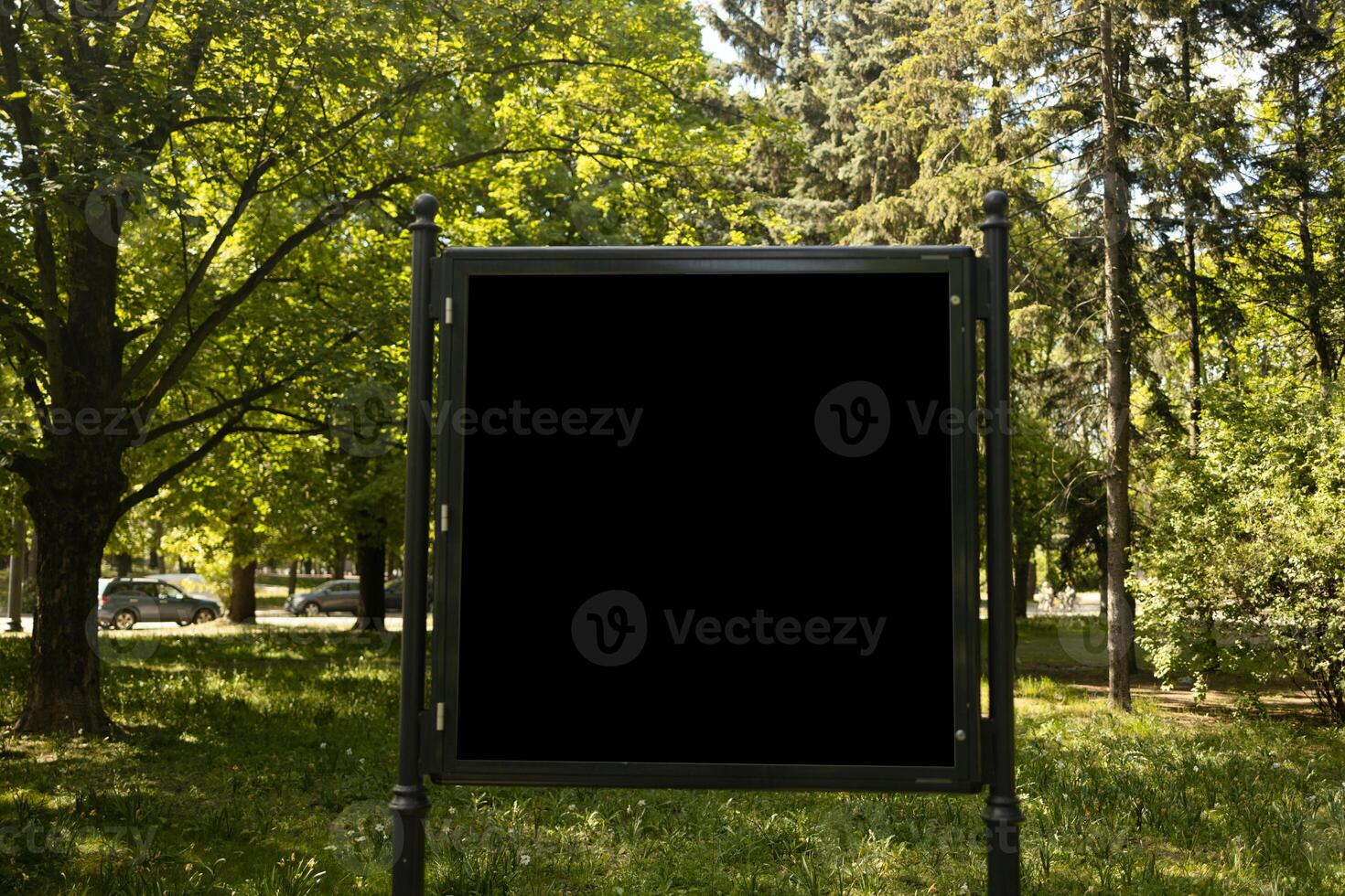 Mockup of the blank street city outdoor advertising square billboard in black frame at park entrance photo