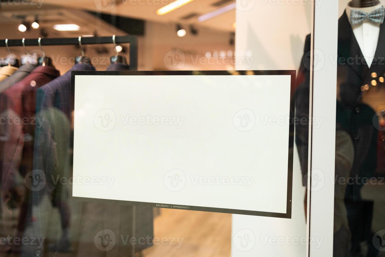 White paper poster mockup board displayed inside on window clothes shop. Marketing and business concept. photo