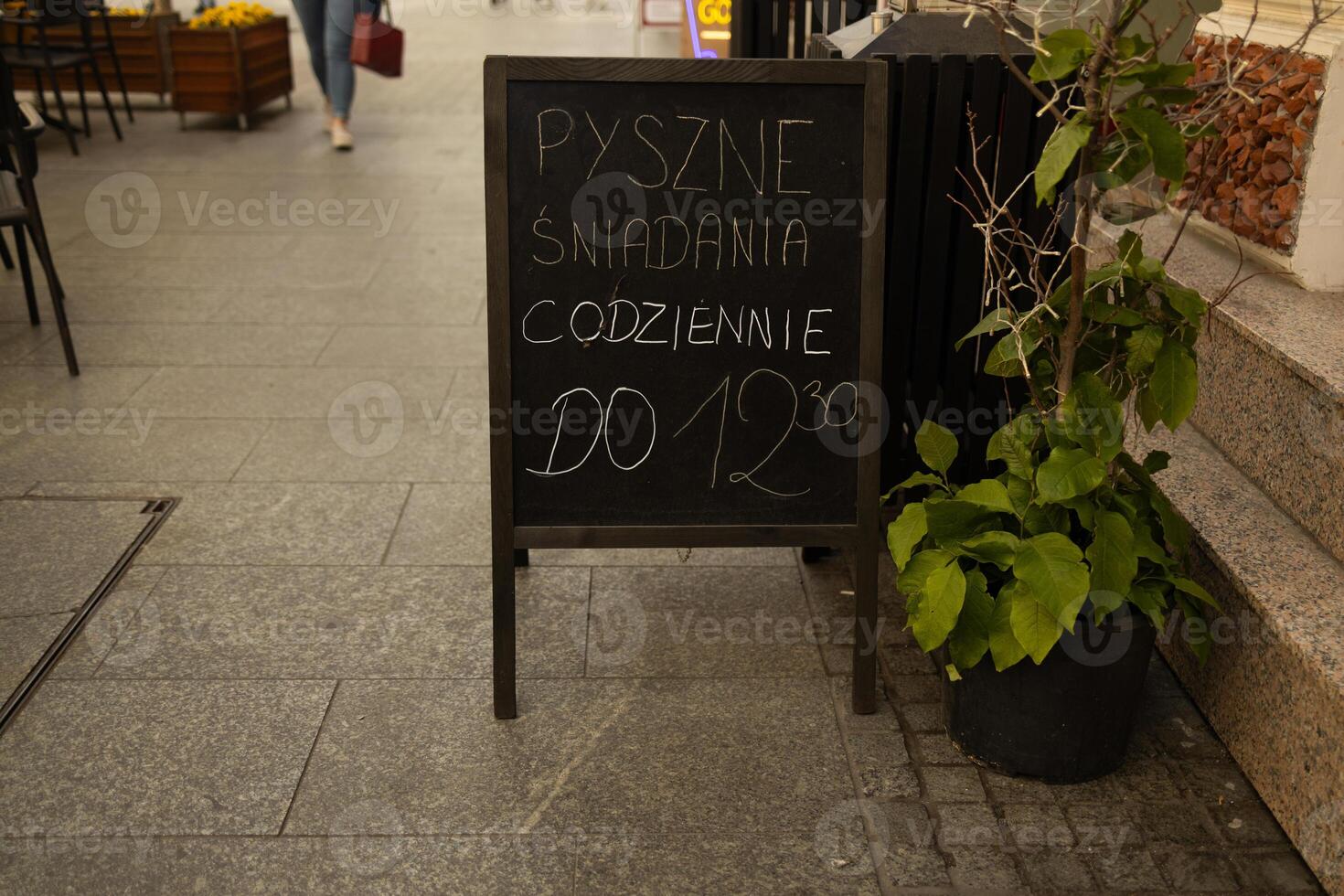 Vertical menu board with text Puszne sniadania codziennie do 12.30 at city street photo