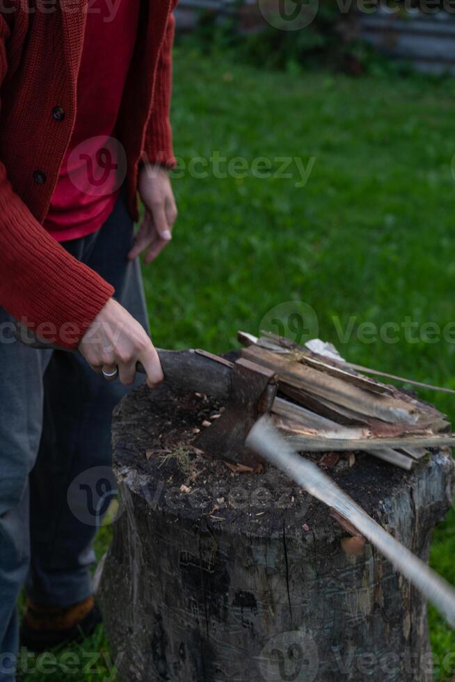 A man is chopping wood for a bonfir A man is chopping small firewood. Evening photo