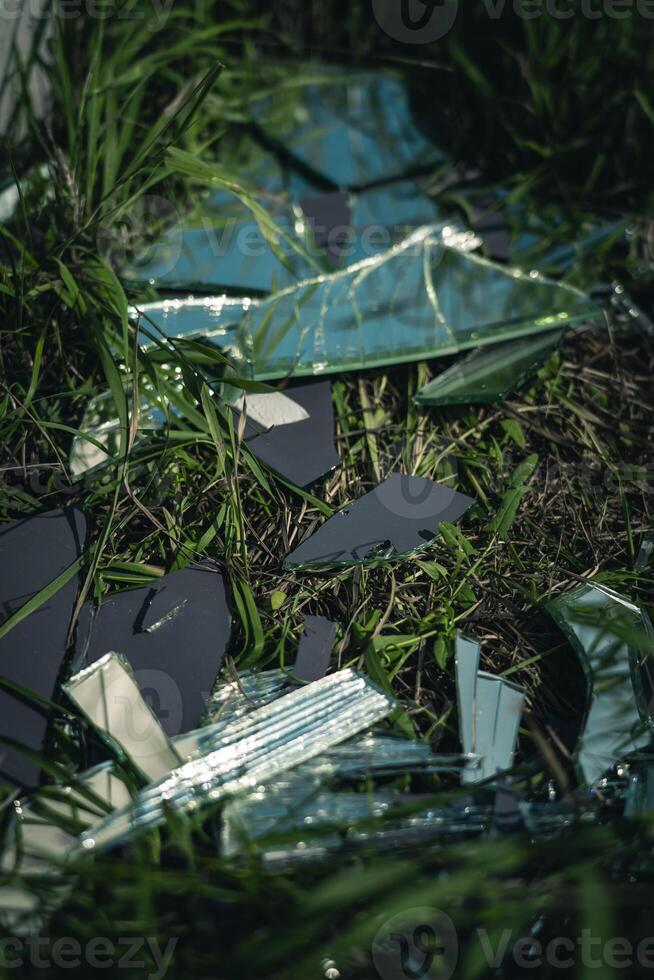 A broken mirror, lying in pieces on the grass, next to the road photo