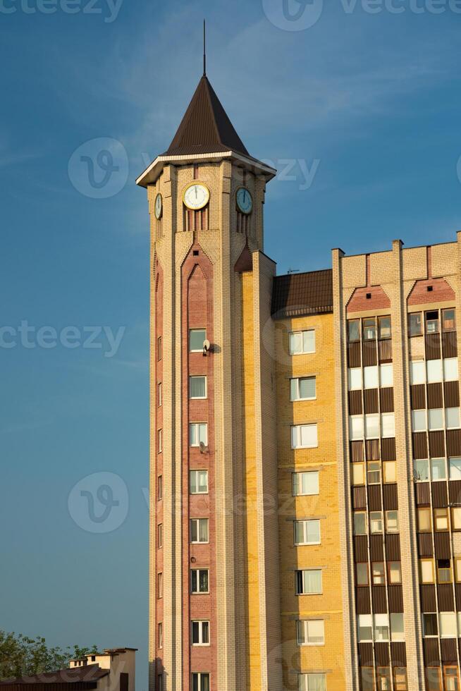 A tall, cone-shaped tower building in the city. Street clock on the tower photo