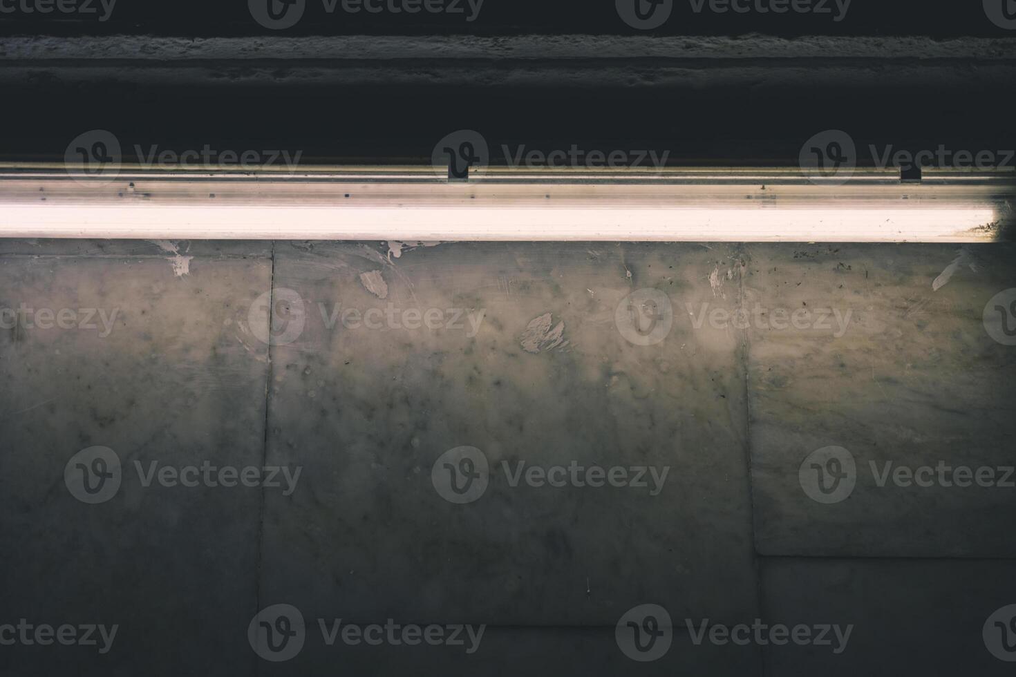 A fluorescent lamp illuminates a marble wall in the subway photo