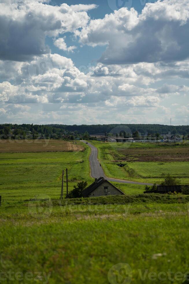 An asphalt road in the distance between fields. Thick clouds over the road photo